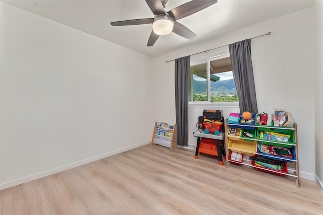 recreation room with a ceiling fan, baseboards, and wood finished floors