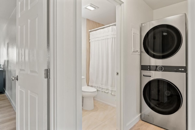 clothes washing area featuring laundry area, visible vents, stacked washing maching and dryer, baseboards, and light tile patterned flooring