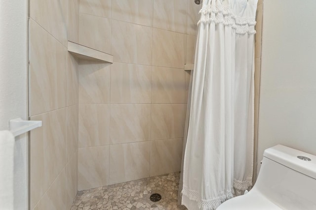 bathroom featuring a tile shower and toilet