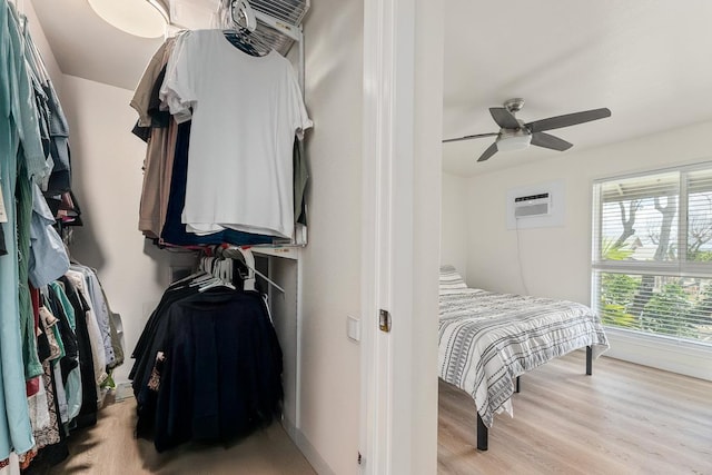 interior space with an AC wall unit, ceiling fan, and light wood-style flooring
