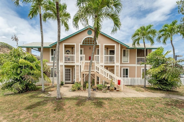 view of front of home with fence, stairway, and a front yard