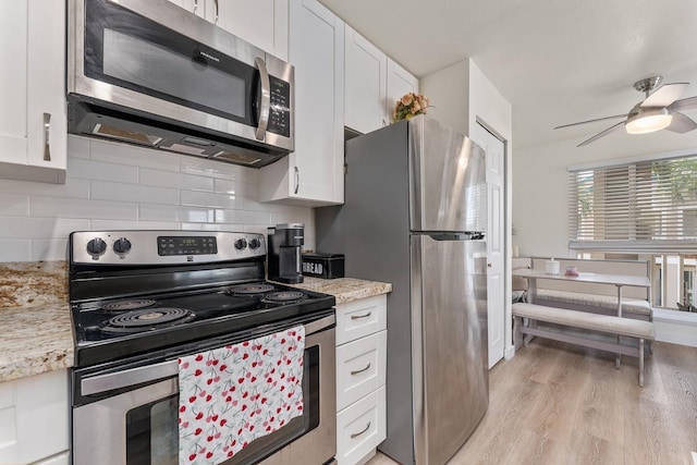 kitchen with a ceiling fan, backsplash, light wood-type flooring, white cabinets, and stainless steel appliances