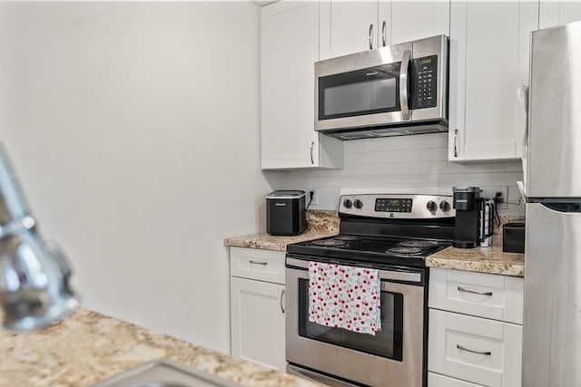 kitchen featuring light stone counters, white cabinets, backsplash, and stainless steel appliances