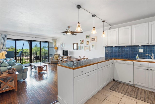 kitchen with pendant lighting, white cabinetry, sink, white dishwasher, and kitchen peninsula