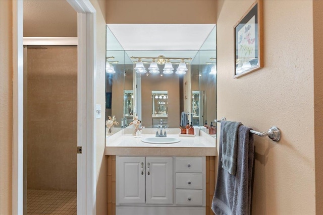 bathroom with a tile shower and vanity