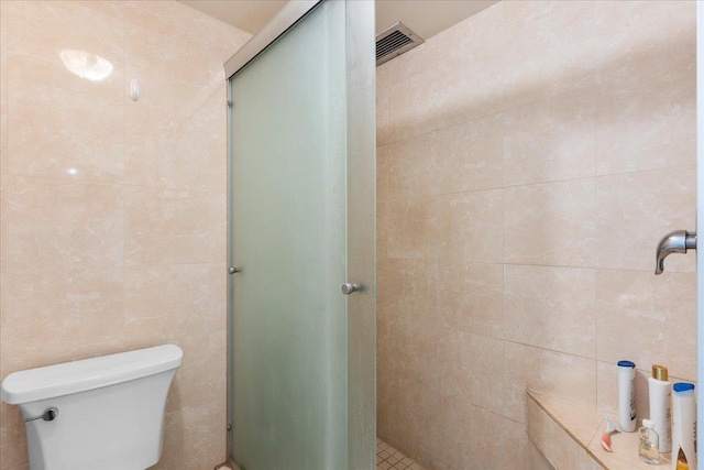 bathroom featuring tile walls, toilet, and walk in shower