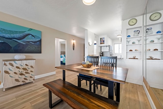 dining room featuring a textured ceiling and light wood-type flooring