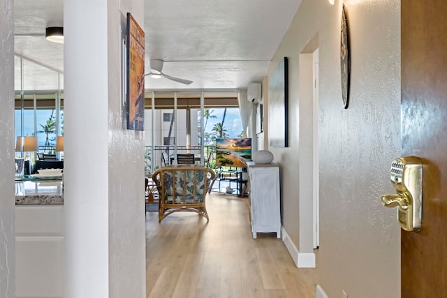 corridor featuring a wall unit AC, light wood-type flooring, and floor to ceiling windows