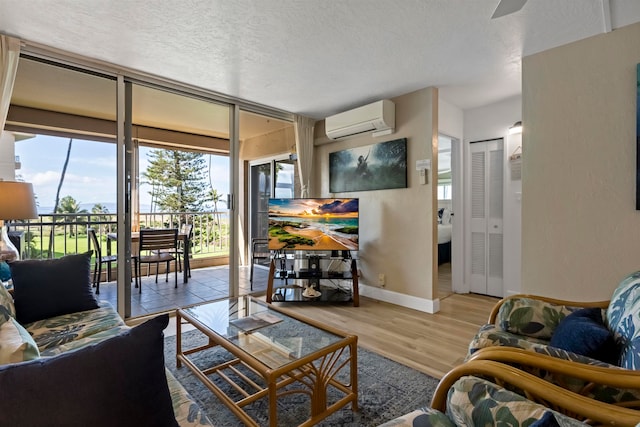 living room with a textured ceiling, a wall mounted air conditioner, and light hardwood / wood-style floors