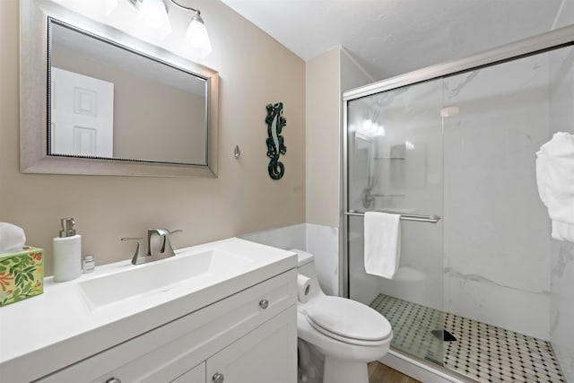 bathroom featuring vanity, a shower with shower door, and toilet