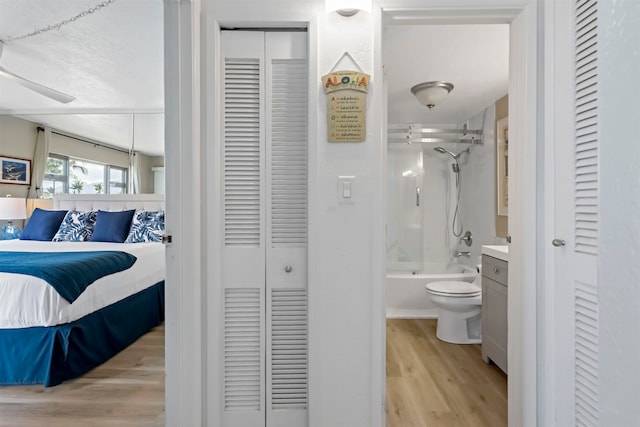 bedroom featuring light hardwood / wood-style flooring, ensuite bath, and ceiling fan