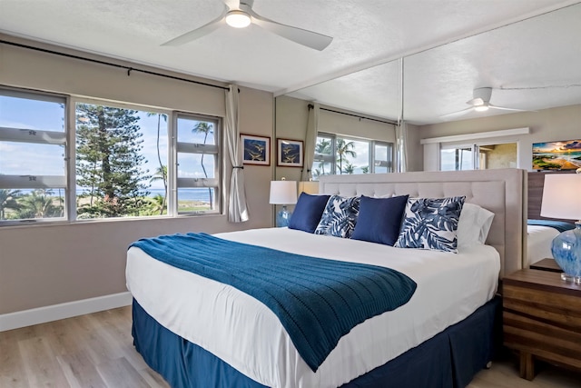 bedroom with multiple windows, hardwood / wood-style floors, and ceiling fan