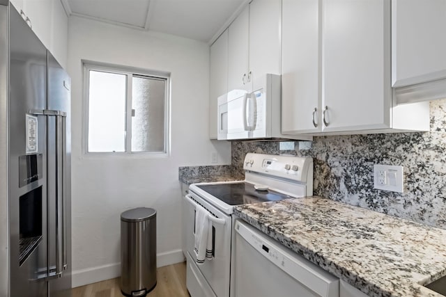 kitchen with backsplash, white cabinetry, light stone countertops, light wood-type flooring, and stainless steel appliances