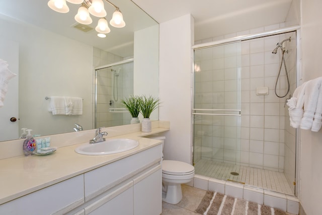 bathroom featuring toilet, vanity, tile patterned flooring, and a shower with door