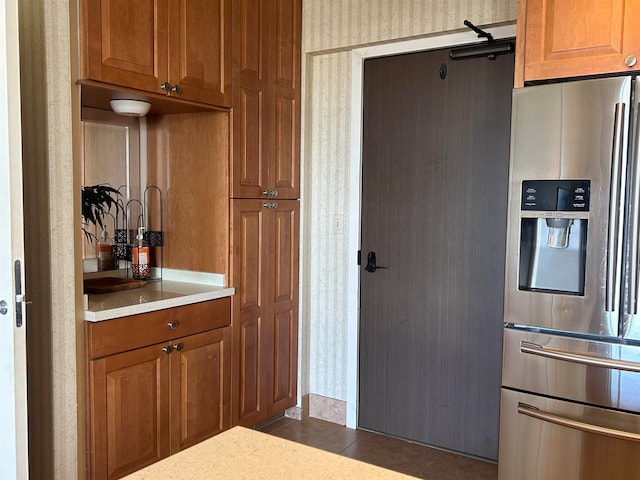 kitchen with dark tile flooring and stainless steel refrigerator with ice dispenser