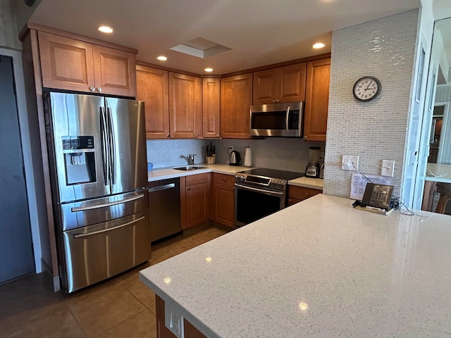 kitchen with stainless steel appliances, sink, light stone countertops, and tile flooring