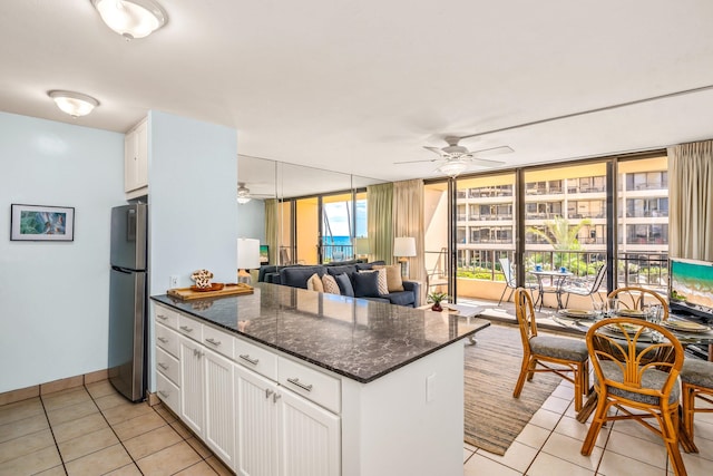 kitchen featuring stainless steel refrigerator, white cabinets, floor to ceiling windows, light tile floors, and ceiling fan