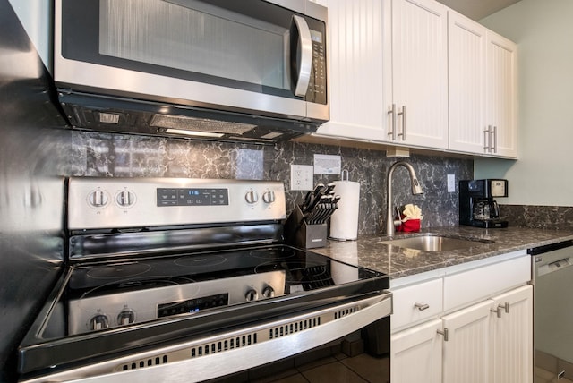 kitchen with sink, appliances with stainless steel finishes, tile floors, tasteful backsplash, and white cabinetry