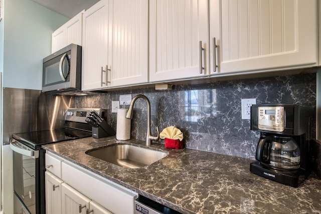 kitchen with appliances with stainless steel finishes, sink, tasteful backsplash, and white cabinets