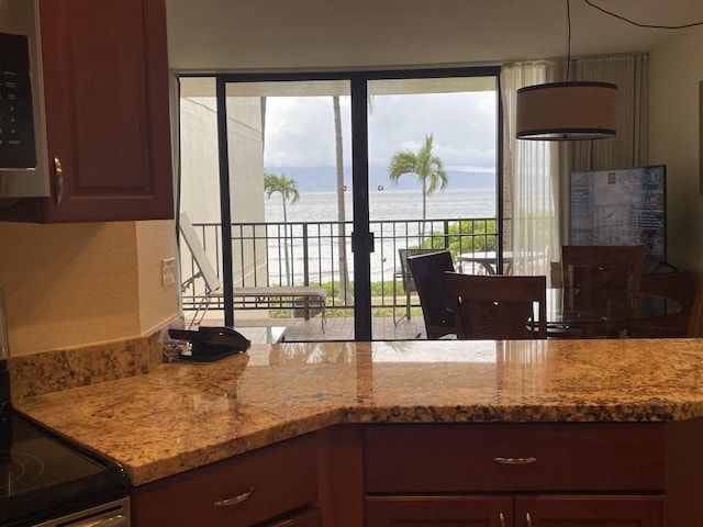 kitchen featuring a water view, light stone counters, and stainless steel appliances