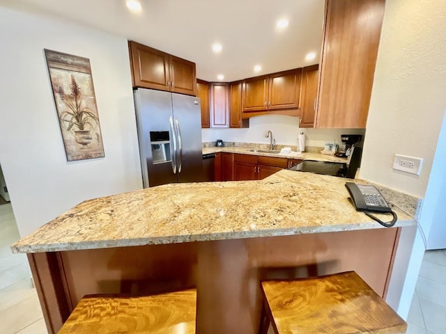 kitchen with kitchen peninsula, stainless steel fridge with ice dispenser, and light stone countertops