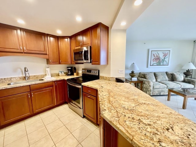 kitchen with light stone countertops, light tile patterned floors, stainless steel appliances, and sink