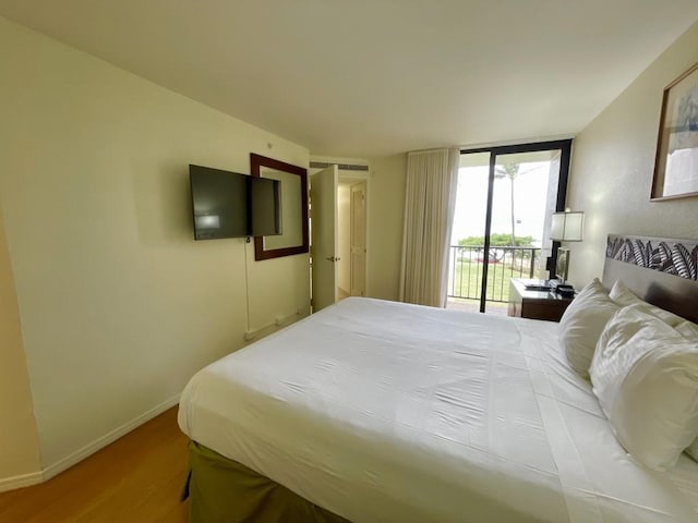 bedroom featuring access to outside, floor to ceiling windows, and hardwood / wood-style floors