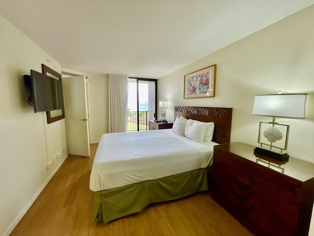 bedroom with a wall of windows, light wood-type flooring, and access to outside