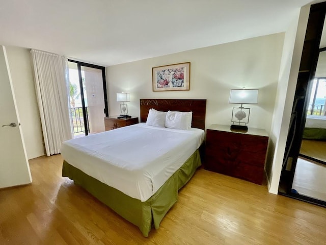 bedroom featuring access to exterior, light wood-type flooring, and multiple windows