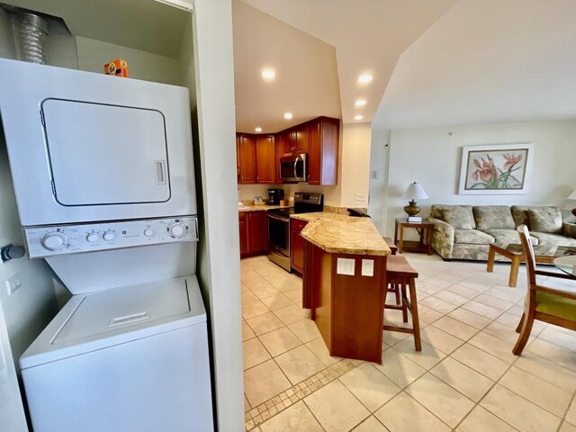 laundry room with stacked washer and dryer and light tile patterned flooring