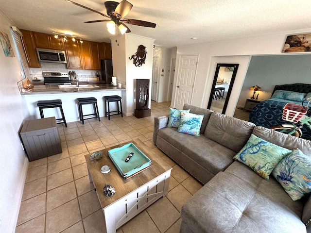 tiled living room featuring a textured ceiling, ceiling fan, and sink