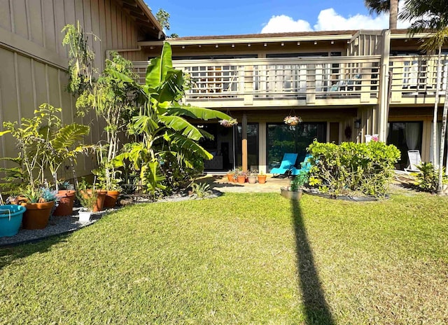 back of property featuring a balcony and a lawn