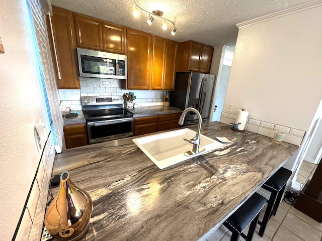 kitchen with appliances with stainless steel finishes, backsplash, ornamental molding, a textured ceiling, and sink