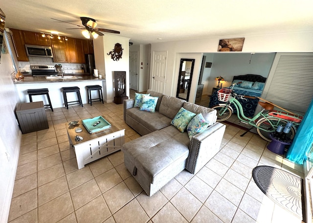 tiled living room with ceiling fan, sink, and a textured ceiling