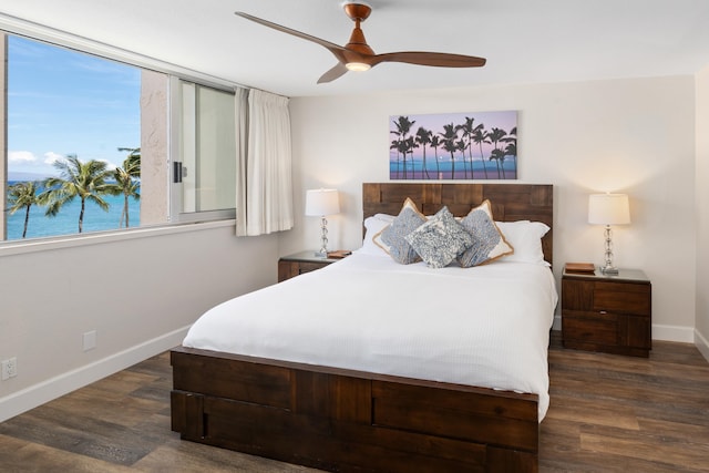 bedroom with dark wood-type flooring, a water view, and ceiling fan