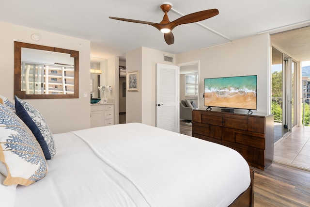 bedroom featuring connected bathroom, ceiling fan, floor to ceiling windows, wood finished floors, and visible vents