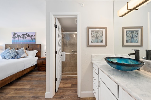 ensuite bathroom with connected bathroom, vanity, baseboards, a shower stall, and wood finished floors