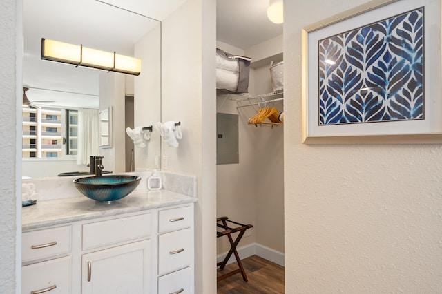 bathroom with electric panel, ceiling fan, vanity, and wood-type flooring