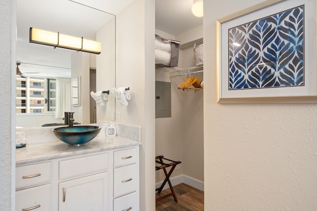 bathroom with vanity, baseboards, wood finished floors, and electric panel