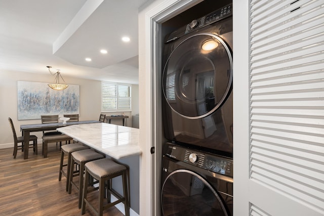 clothes washing area with laundry area, stacked washer / drying machine, baseboards, recessed lighting, and dark wood-type flooring