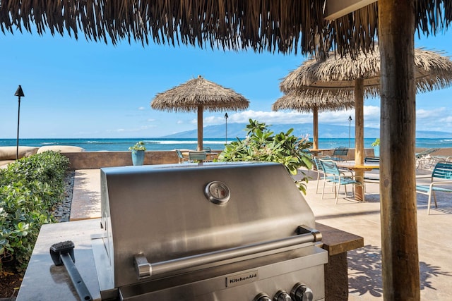 view of patio with a water view and a grill