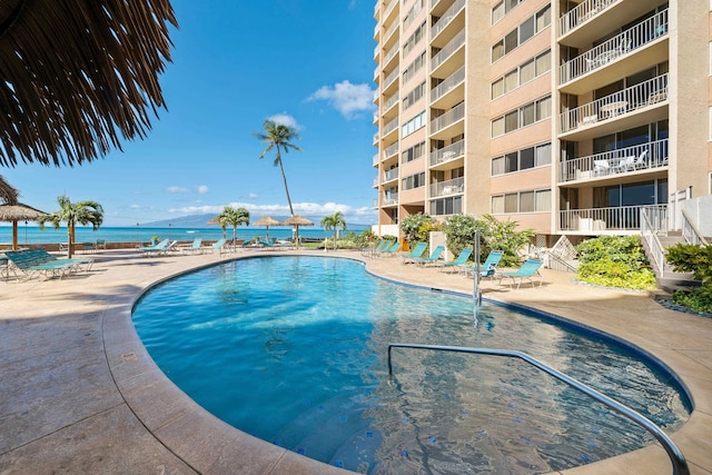 view of pool featuring a water view and a patio area