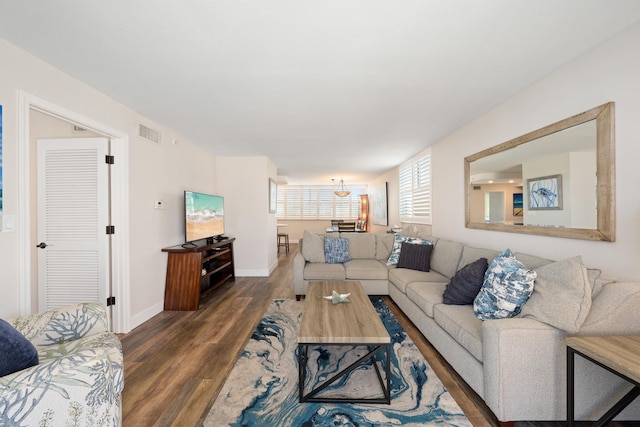 living room featuring baseboards, visible vents, and wood finished floors