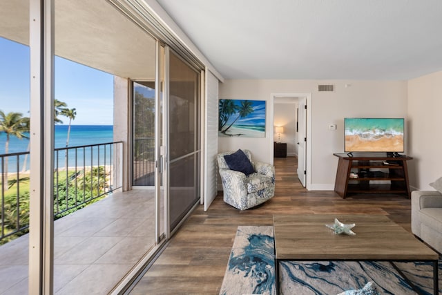 living area featuring a water view, baseboards, wood finished floors, and visible vents