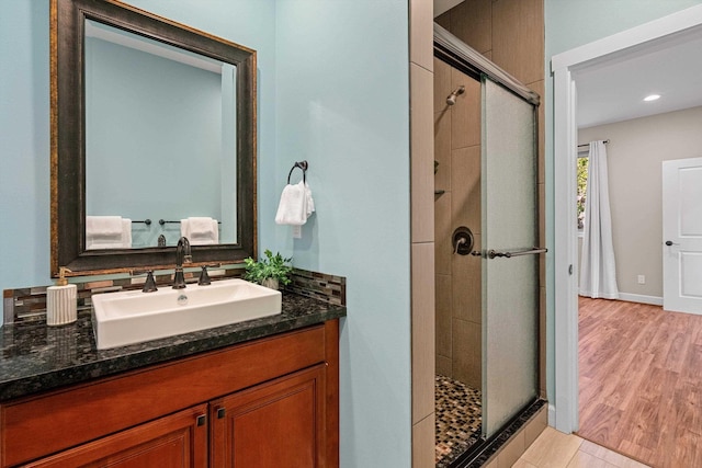 full bathroom with a shower stall, vanity, and wood finished floors