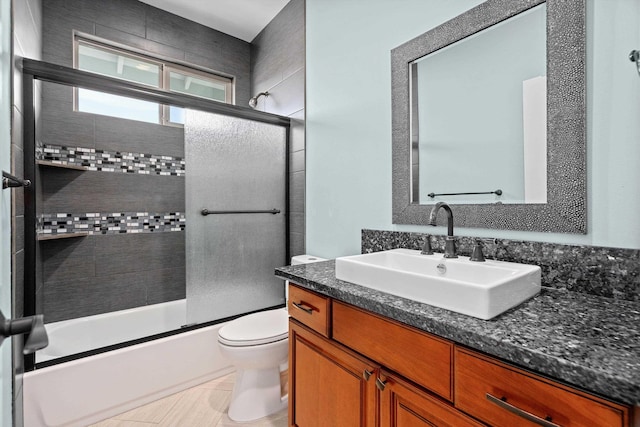 full bathroom with toilet, vanity, and shower / bath combination with glass door