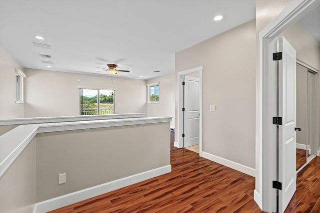 corridor featuring recessed lighting, baseboards, wood finished floors, and an upstairs landing