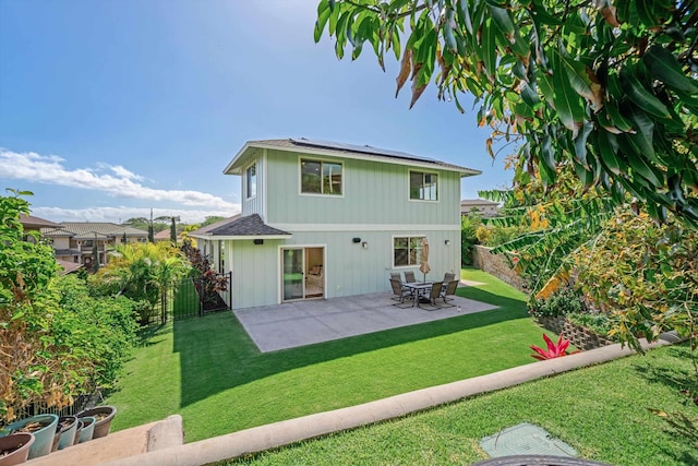 rear view of property featuring roof mounted solar panels, a lawn, a fenced backyard, and a patio area