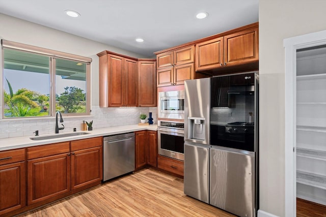 kitchen featuring a sink, light countertops, light wood-style flooring, and stainless steel appliances