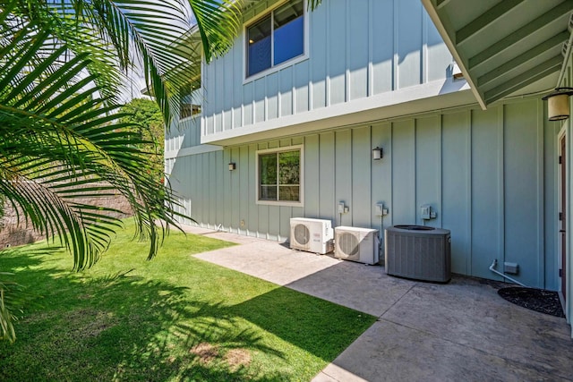 back of house with central air condition unit, a lawn, board and batten siding, and ac unit